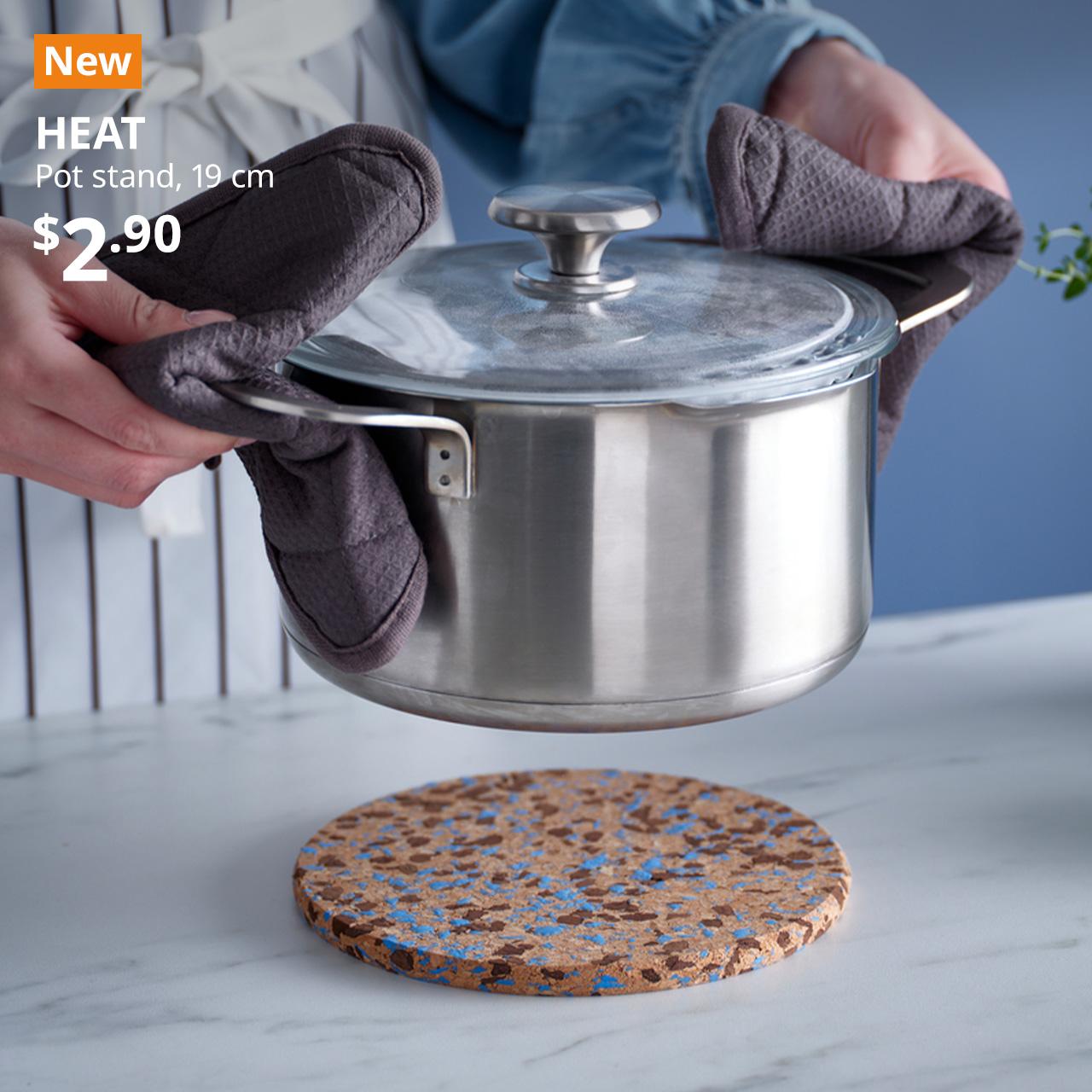 A corked patterened/light blue HEAT pot stand in a kitchen setting. Black text on top left of the image reads: HEAT, Pot stand, 19 cm. Price: $2.90.