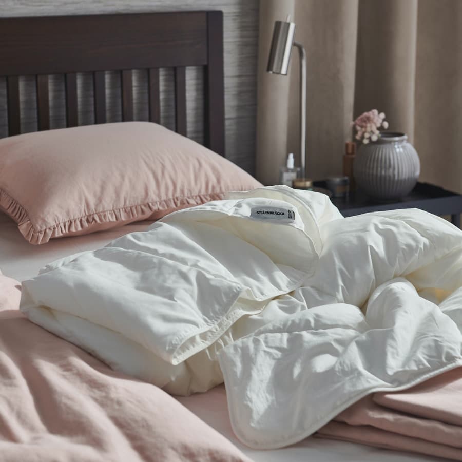 A corner of bed with STJÄRNBRÄCKA duvet placed at the center of it.