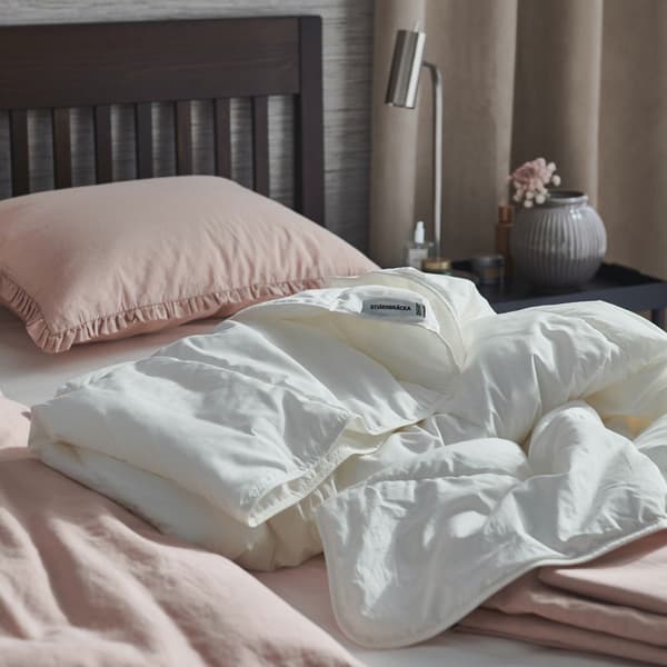 A corner of bed with STJÄRNBRÄCKA duvet placed at the center of it. 