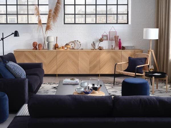 A cosy living room with dark blue seating and BESTÅ wooden furniture for storage.