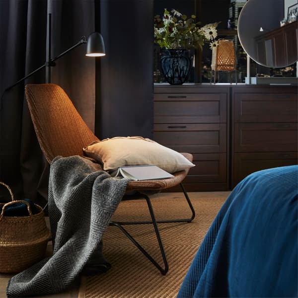 A cosy reading corner in a bedroom, with an IKEA RÅDVIKEN dark brown/black armchair and a SKURUP black floor reading lamp.
