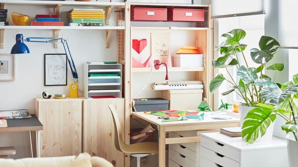 À côté d’un rangement IVAR utilisant toute la largeur du mur, une table dépliée recouverte de papier coloré en guise d’espace de travail.