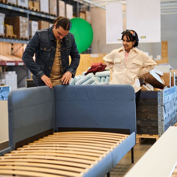 A couple inspecting a bed frame at the As-is section in an IKEA store.