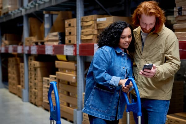 A couple is standing in an IKEA store and looking at a phone.