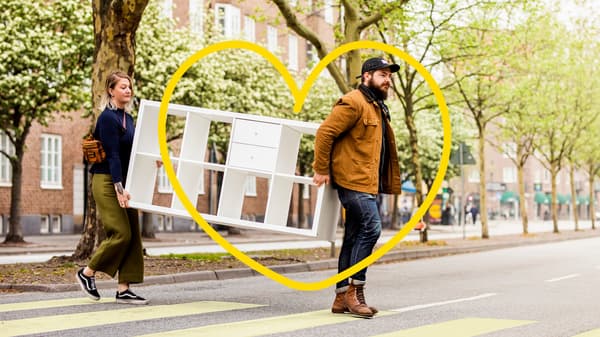 A couple is walking across a street carrying a shelf.