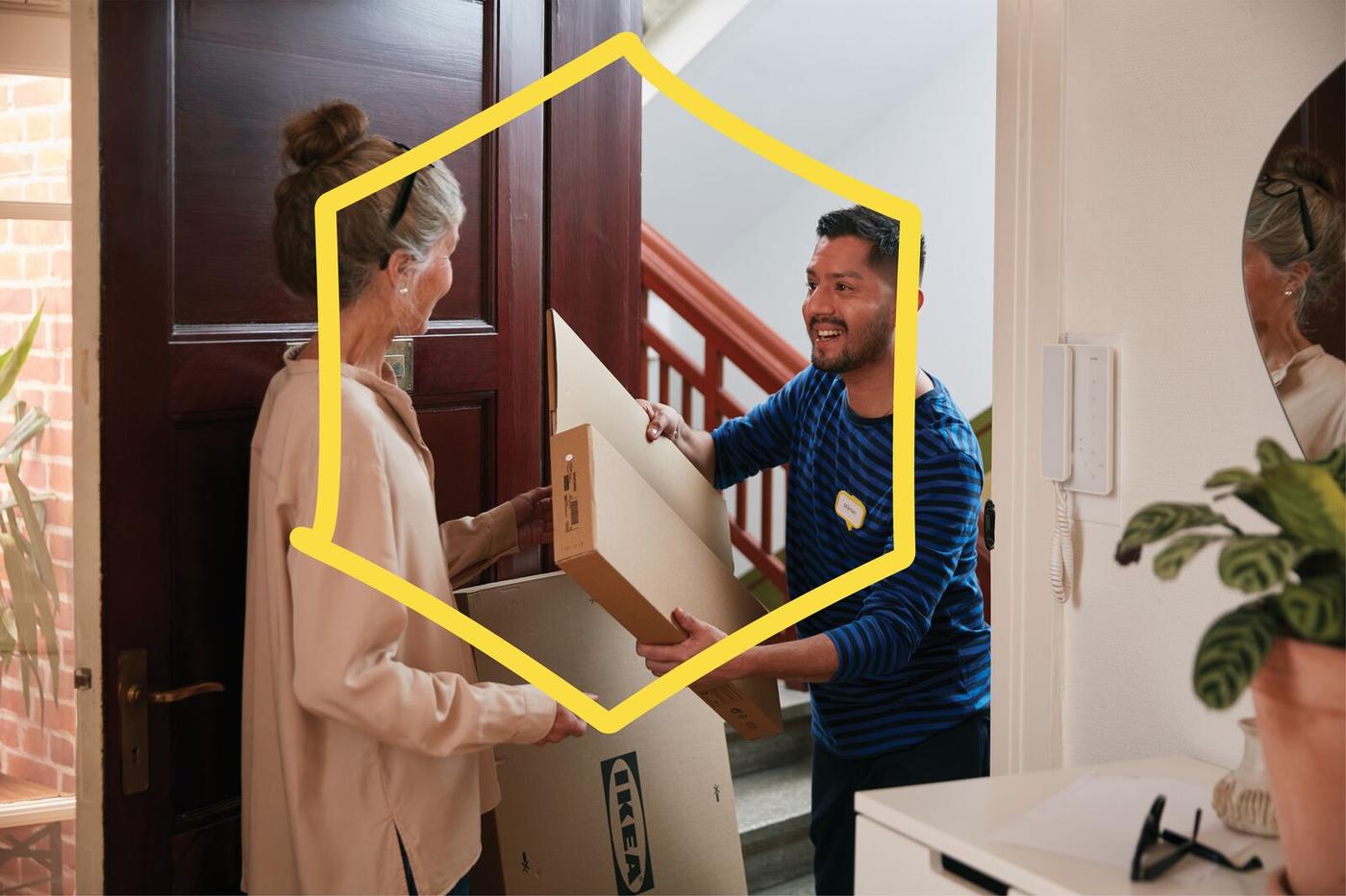 A courier hands IKEA packages to a woman at her front door