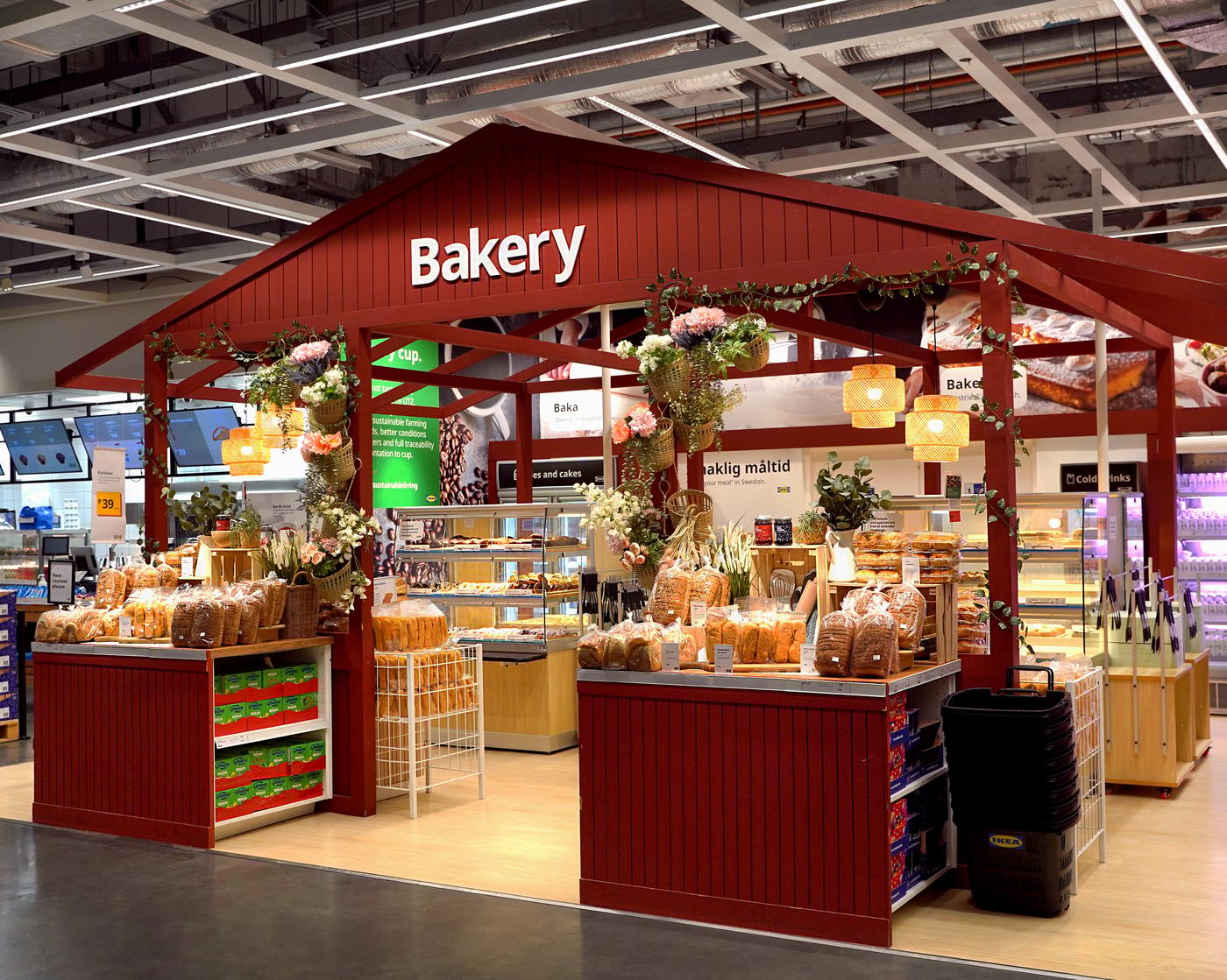 A cozy bakery stall in a store, with a red wooden frame adorned with floral decorations. There's an assortment of bread and pastries displayed invitingly.