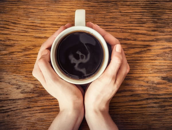 A cup of coffee between two hands.