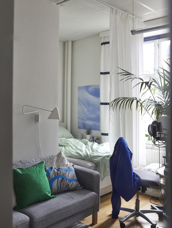 A curtain separates a sofa and bed.