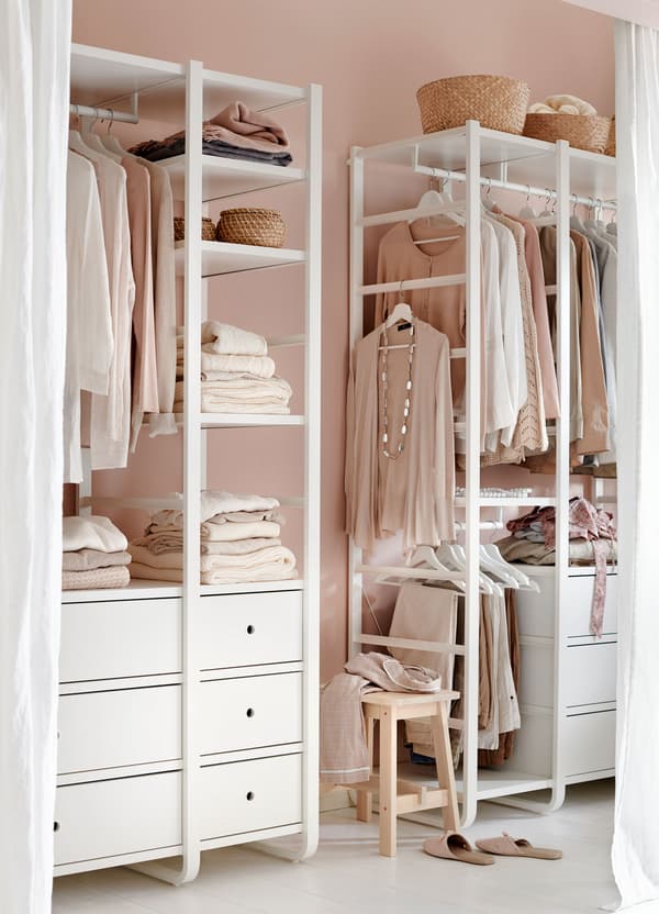 A curtained nook containing an IKEA ELVARLI open storage system filled with clothing.