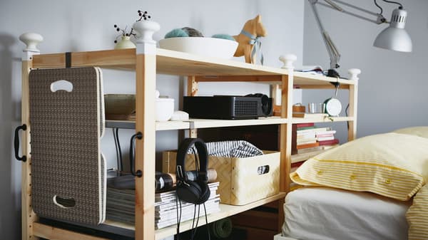 A customised IVAR shelving unit nestled behind a bed.