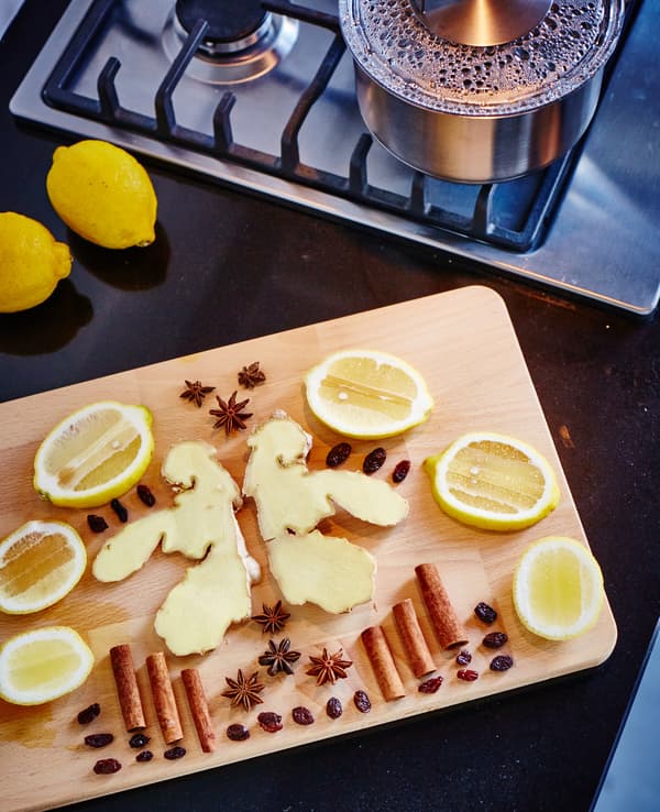 A cutting board with pieces of lemon, cinnamon, ginger, cloves and raisins.
