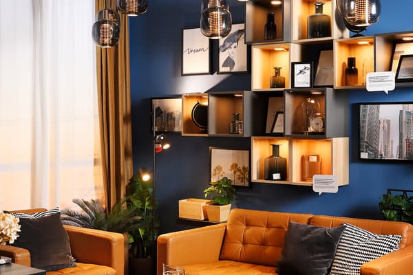 A dark blue room featuring three leather sofas and a black coffee table with a glass jug and glasses on a wooden tray.