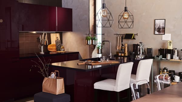 A dark brown kitchen with METOD cabinet and an island. White bar stools at the island, and two BRUNSTA lamps hang overhead.