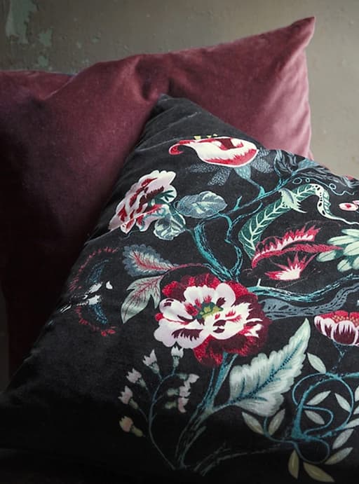 A dark floral and red velvet cushion.