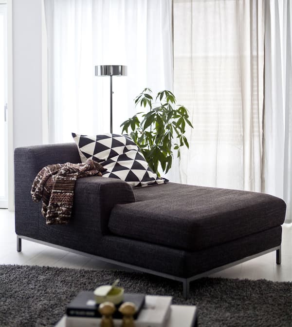 A dark grey chaise longue in a monochrome living space.