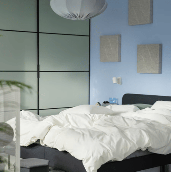 A dark grey SLATTUM upholstered bed, with a STUK storage case underneath it, stands on a green/off-white RINGKLOCKA rug.