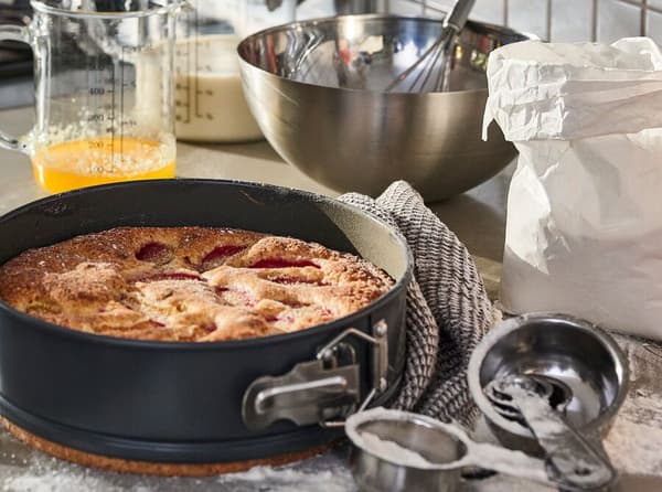 A dark grey STRANDFLY springform pan on a kitchen counter with other baking accessories. 