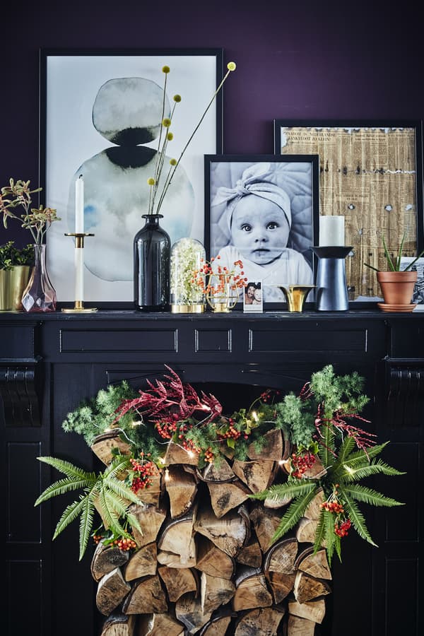 A dark painted fireplace with festive decoration and personal objects displayed on top.
