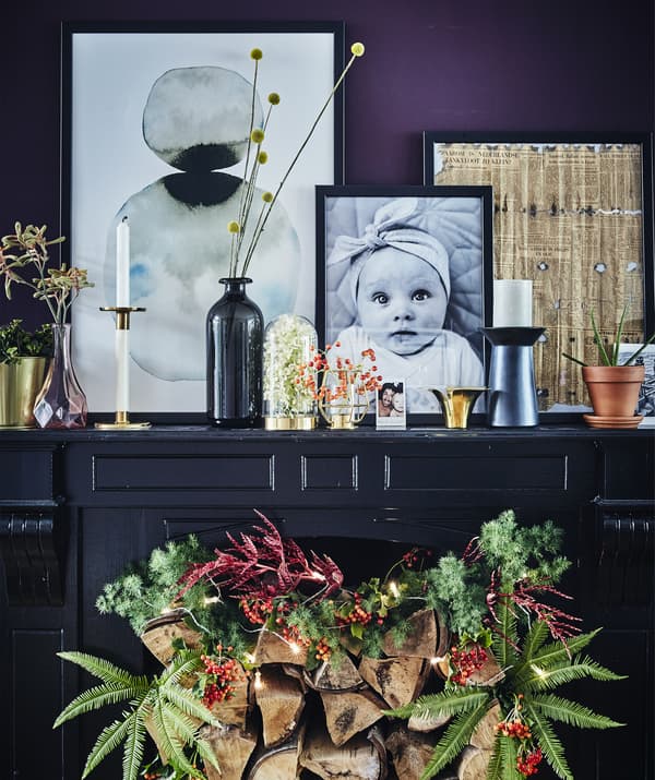 A dark painted fireplace with festive decoration and personal objects displayed on top.