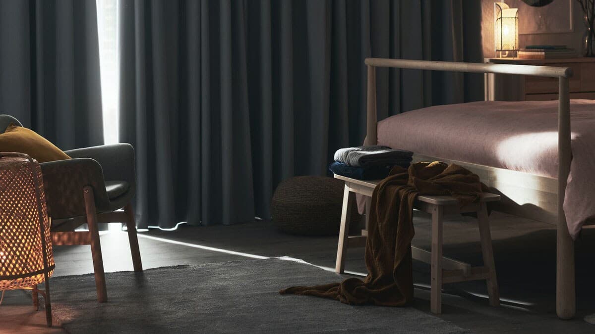 A darkened bedroom interior with slightly opened HILLEBORG block-out curtains.