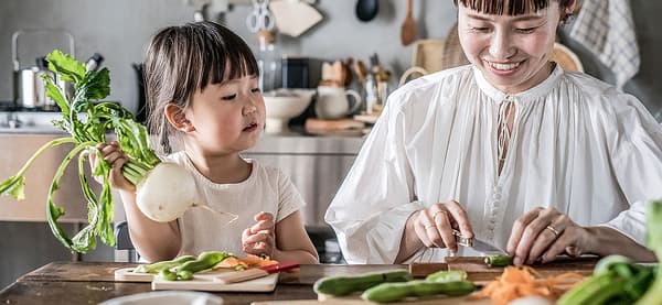 A daughter is cooking with her mother. 