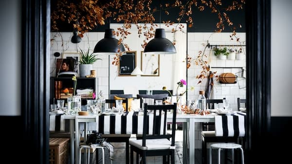 A decked-out black-and-white dining area with brown-black STEFAN chairs and MARIUS stools round two white MELLTORP tables.