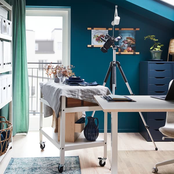 A decorative dinner scene on the top shelf of a trolley with castors. It has been moved next to a camera for a photo shoot.