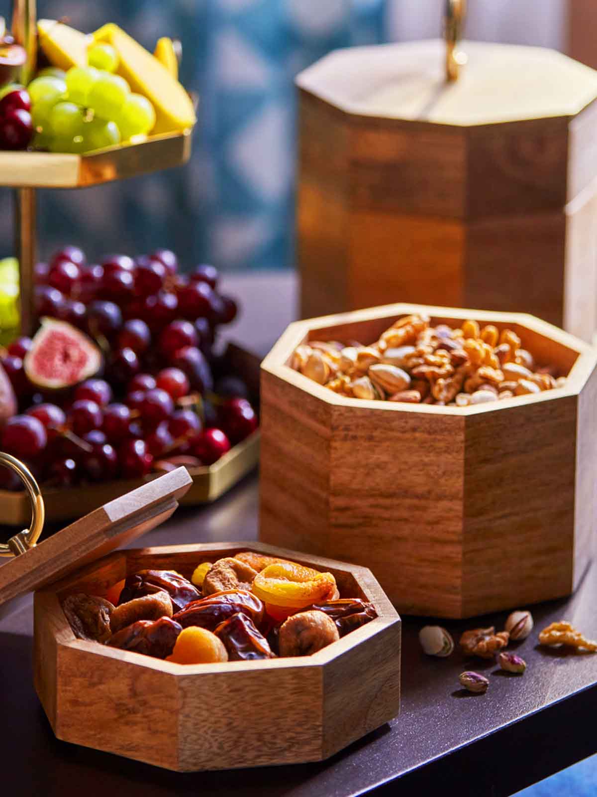  A decorative GOKVÄLLÅ wooden box with three tiers. Each tier is filled with cakes, fruits and snacks.