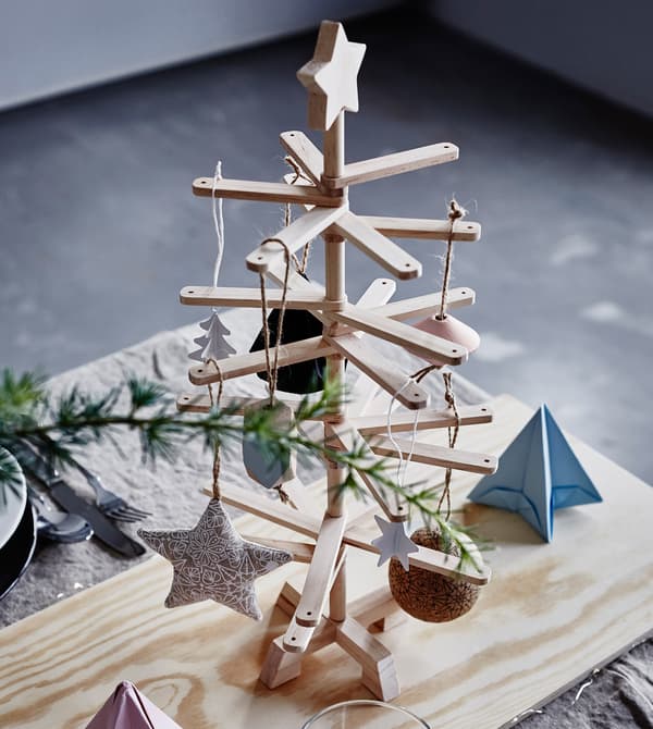 A decorative wooden Christmas tree sits on a dining table.