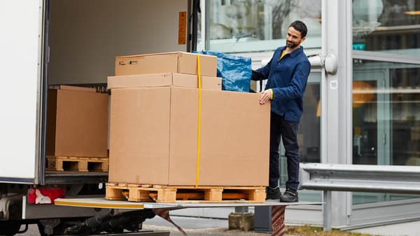 A delivery man with IKEA boxes on the back of a truck.