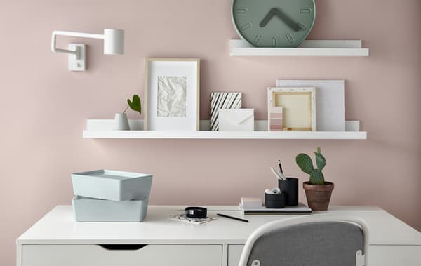 A desk, drawer and chair in a home office set against a wall decorated with big splatters of different coloured paint.