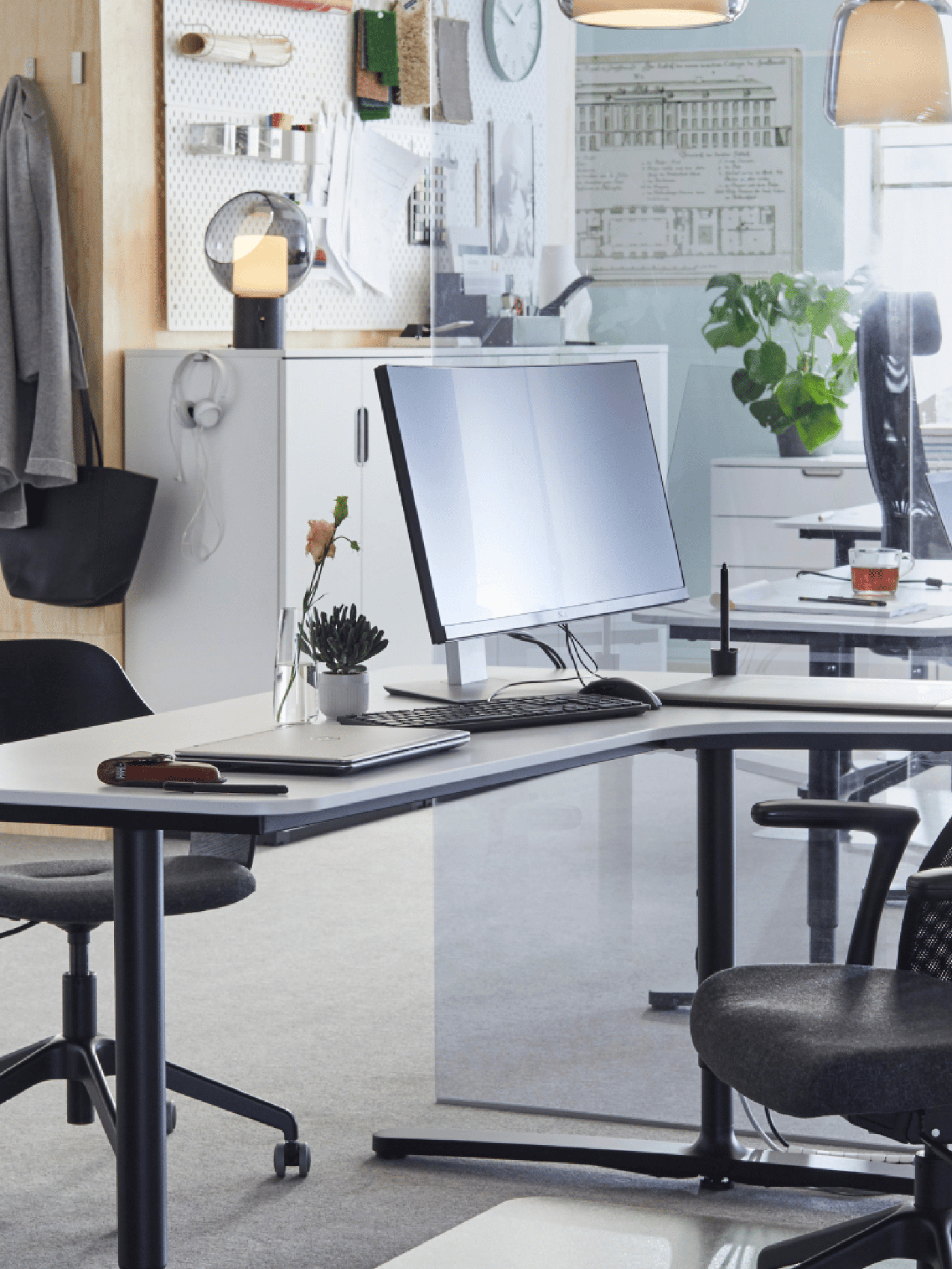 A desk in an office with a computer and a chair on the foreground
