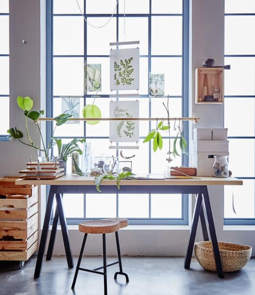 A desk in front of a window is decorated with botanical elements.
