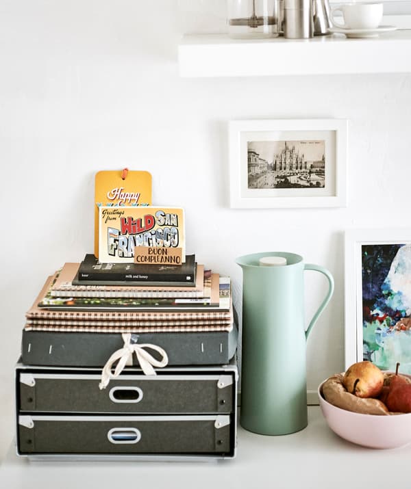A desk organiser, flask, fruit bowl and pictures arranged as a pretty display.