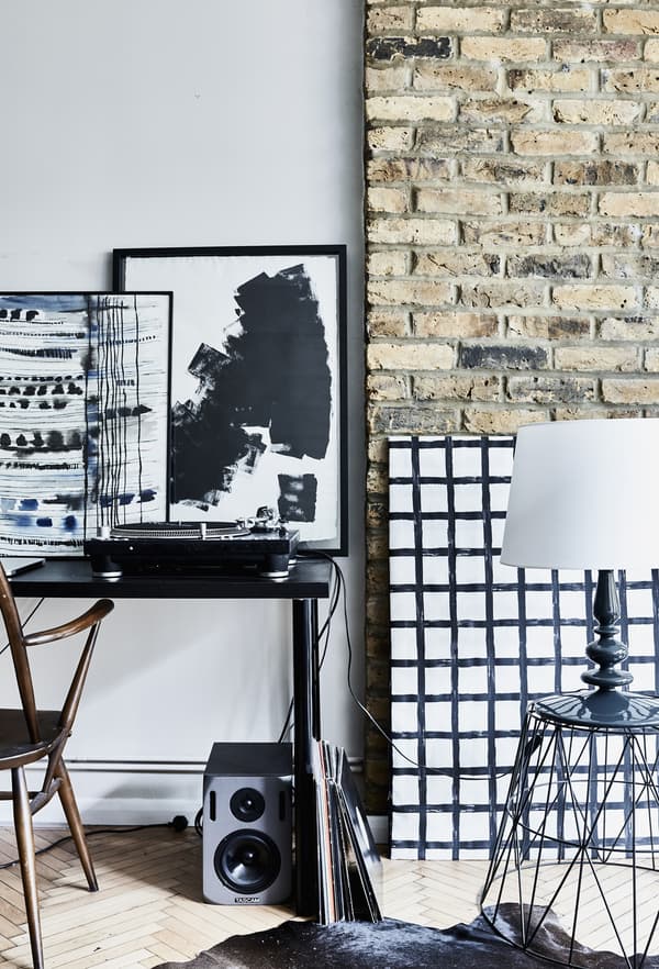 A desk with artwork and an exposed brick wall.