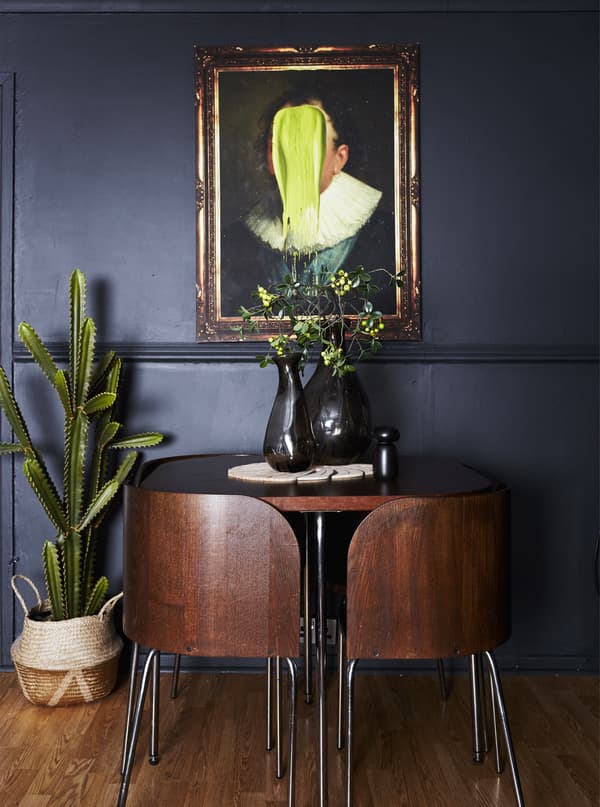 A dining area with a brown table and four chairs with chrome legs, the table is decorated with two black vases.