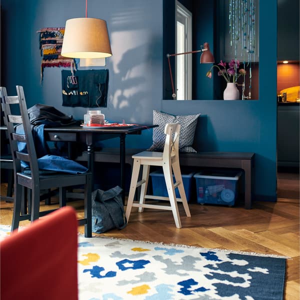 A dining area with an IKEA INGATORP black-brown drop-leaf table and brightly patterned rug.