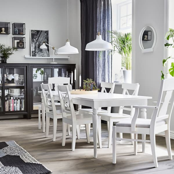 A dining area with white INGATORP extendable dining table and HEMNES black glass door cabinets to store dinnerware.