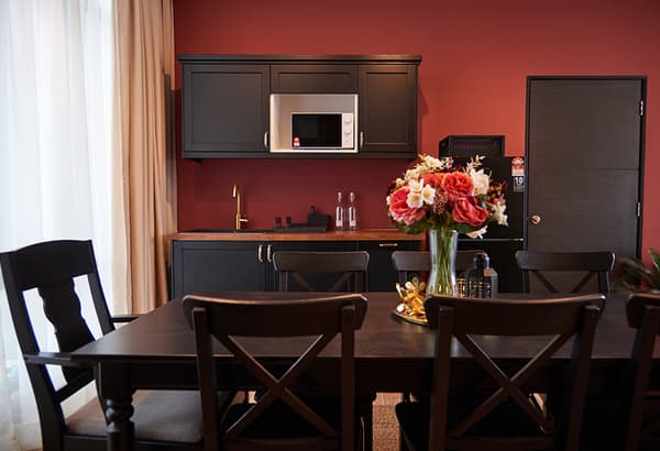A dining room setting featuring a dark wooden table and chairs with a vase and flowers placed on top.