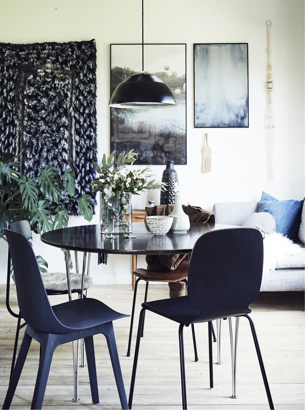 A dining room with pictures, wall hanging and pendant light.