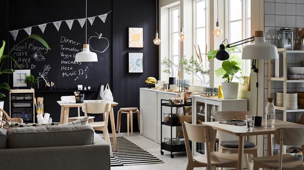 A dining room with three big windows and a blackboard wall has two LISABO tables in ash veneer with matching chairs.