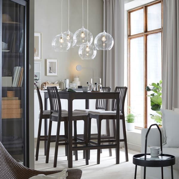 A dining space with EKEDALEN dark grey four-seater bar table and high bar stools and JAKOBSBYN clear glass pendant lampshades.