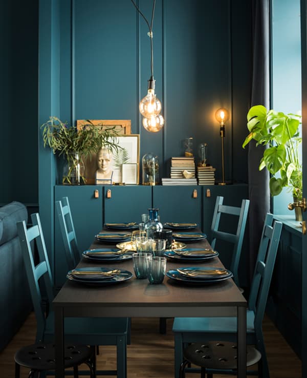 A dining table and chairs are custom painted in the same shade of green, and set with tableware in a similar colur.
