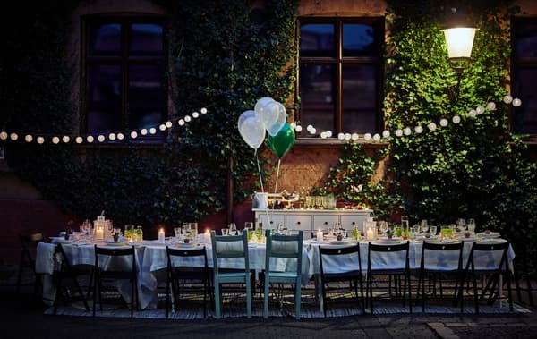 A dining table for a wedding is set up in a courtyard at night time.