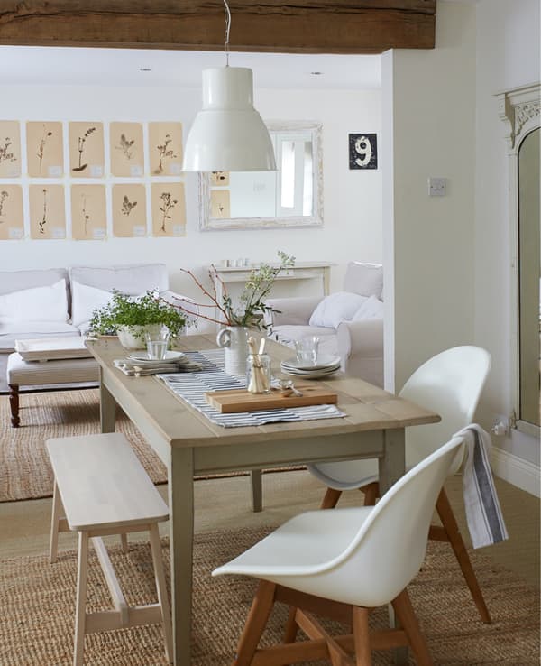 A dining table in an open-plan living area with wooden beams above.