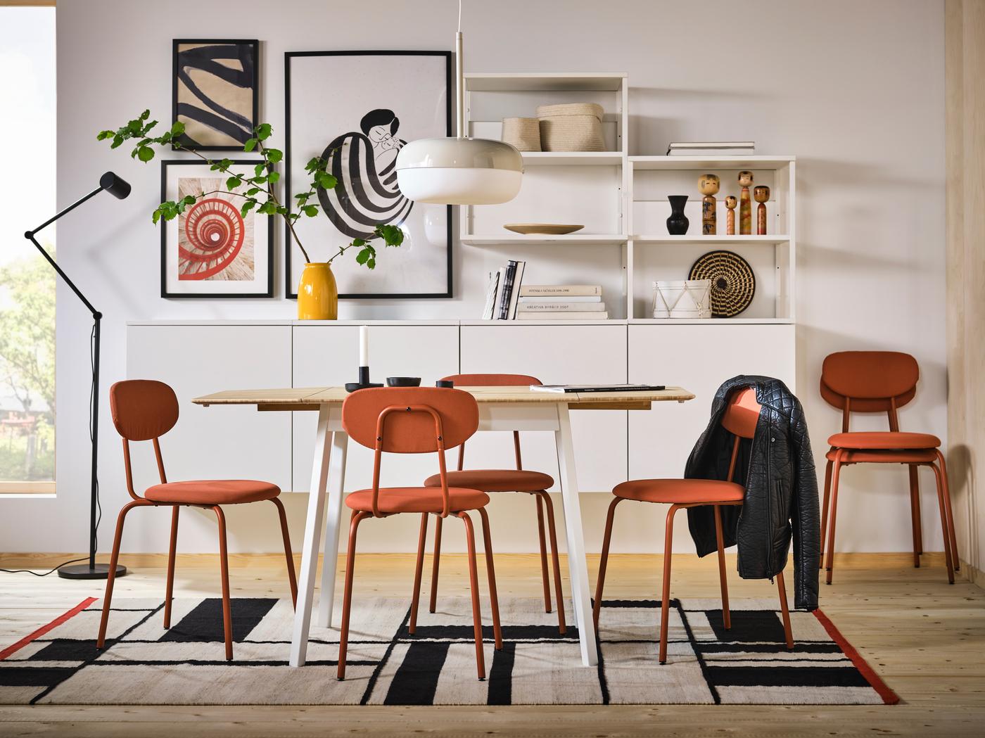 A dining table surrounded by red chairs and a black and white rug 