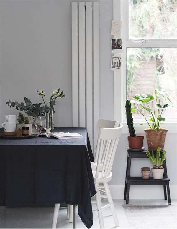 A dining table with dark tablecloth and white dining chairs.