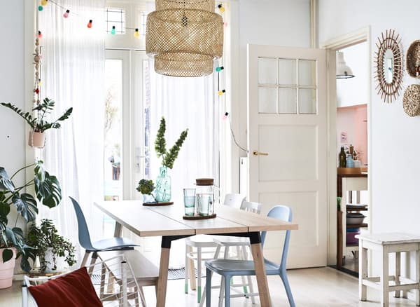 A dining table with white walls and pale wooden table.