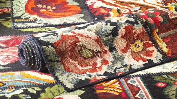 A display of the same rug-  one rolled up and two others laid out flat.